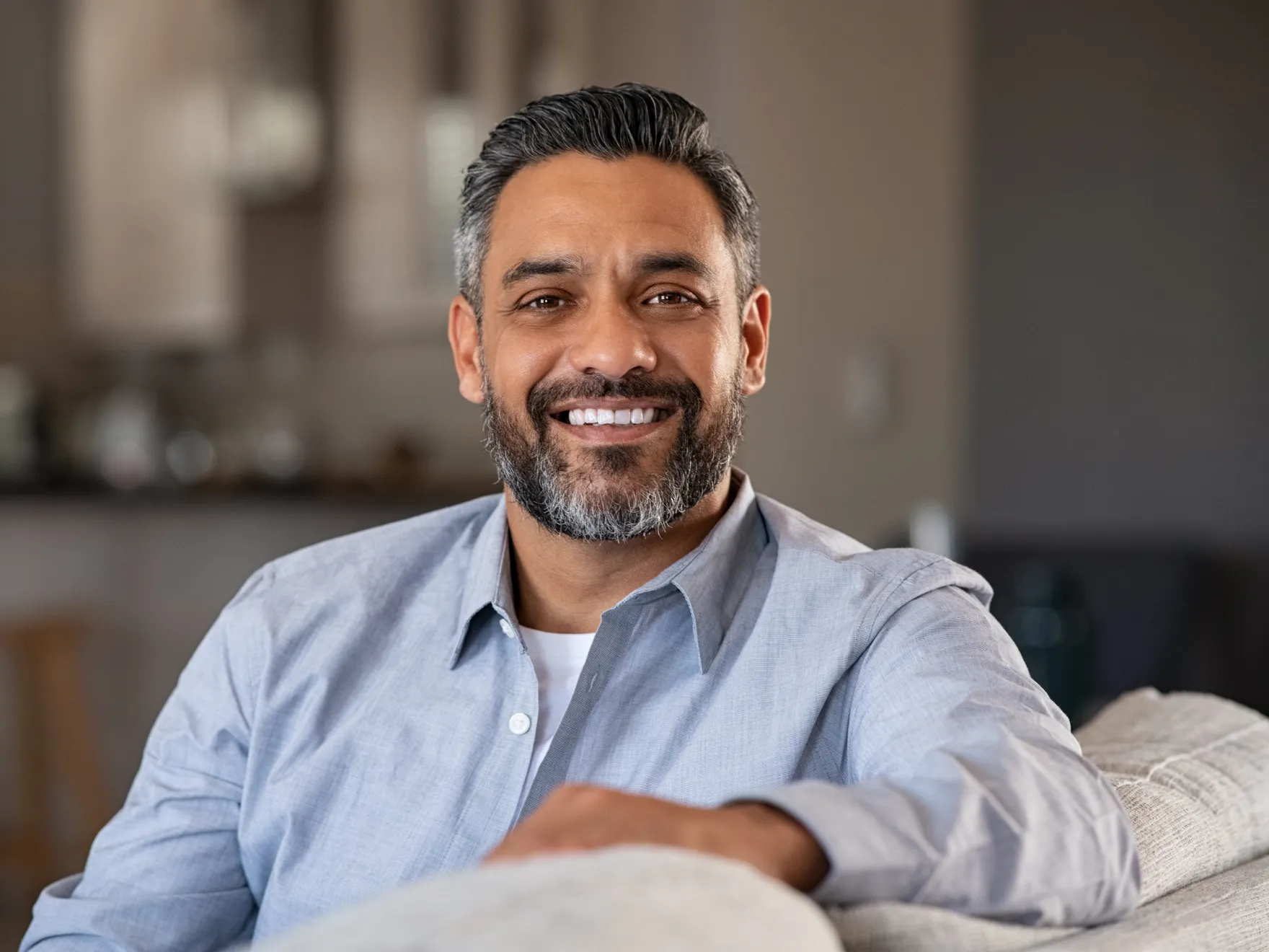 a man sitting on a couch smiling at the camera