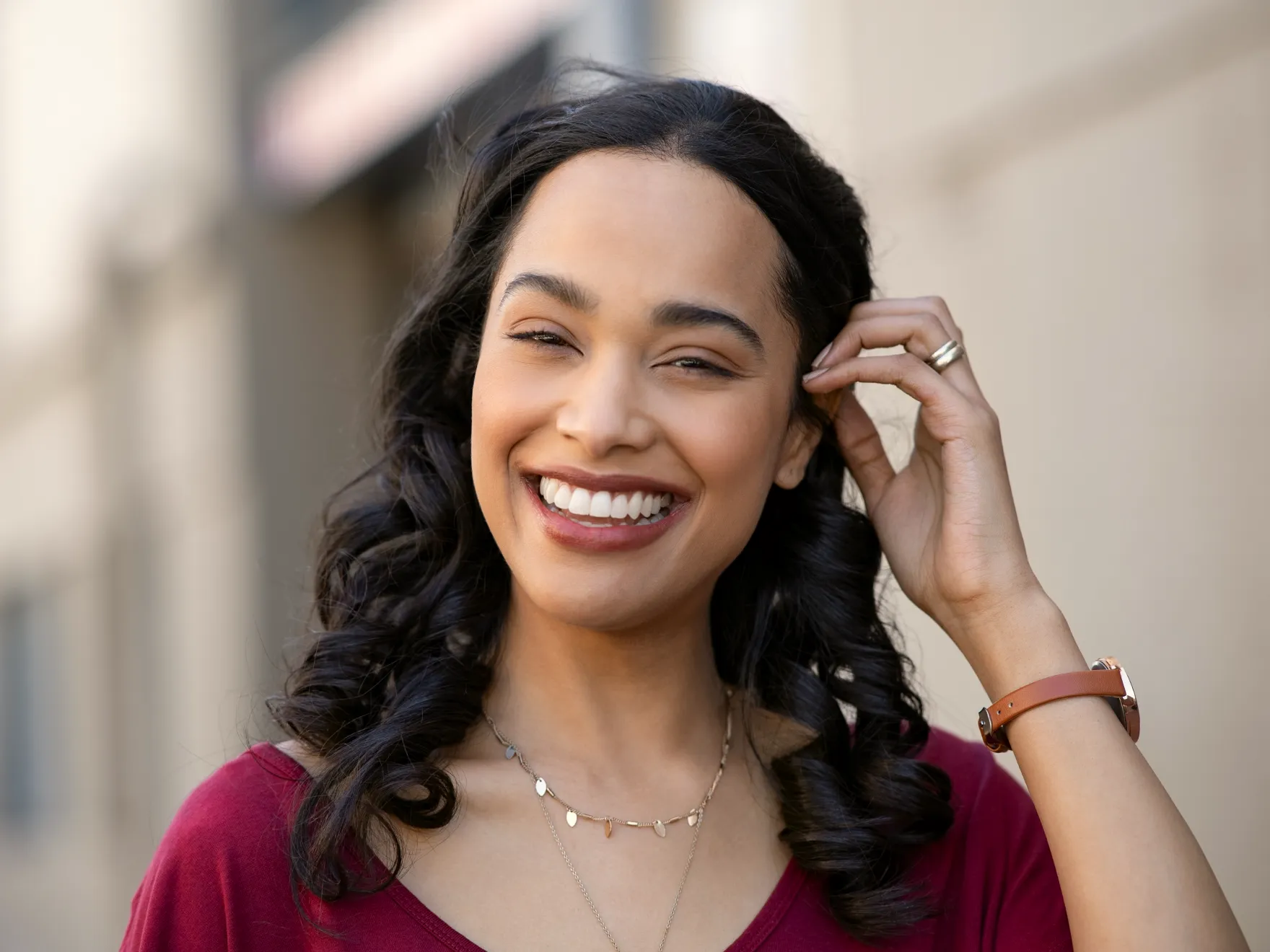 a smiling woman in a red shirt is holding her hand to her ear
