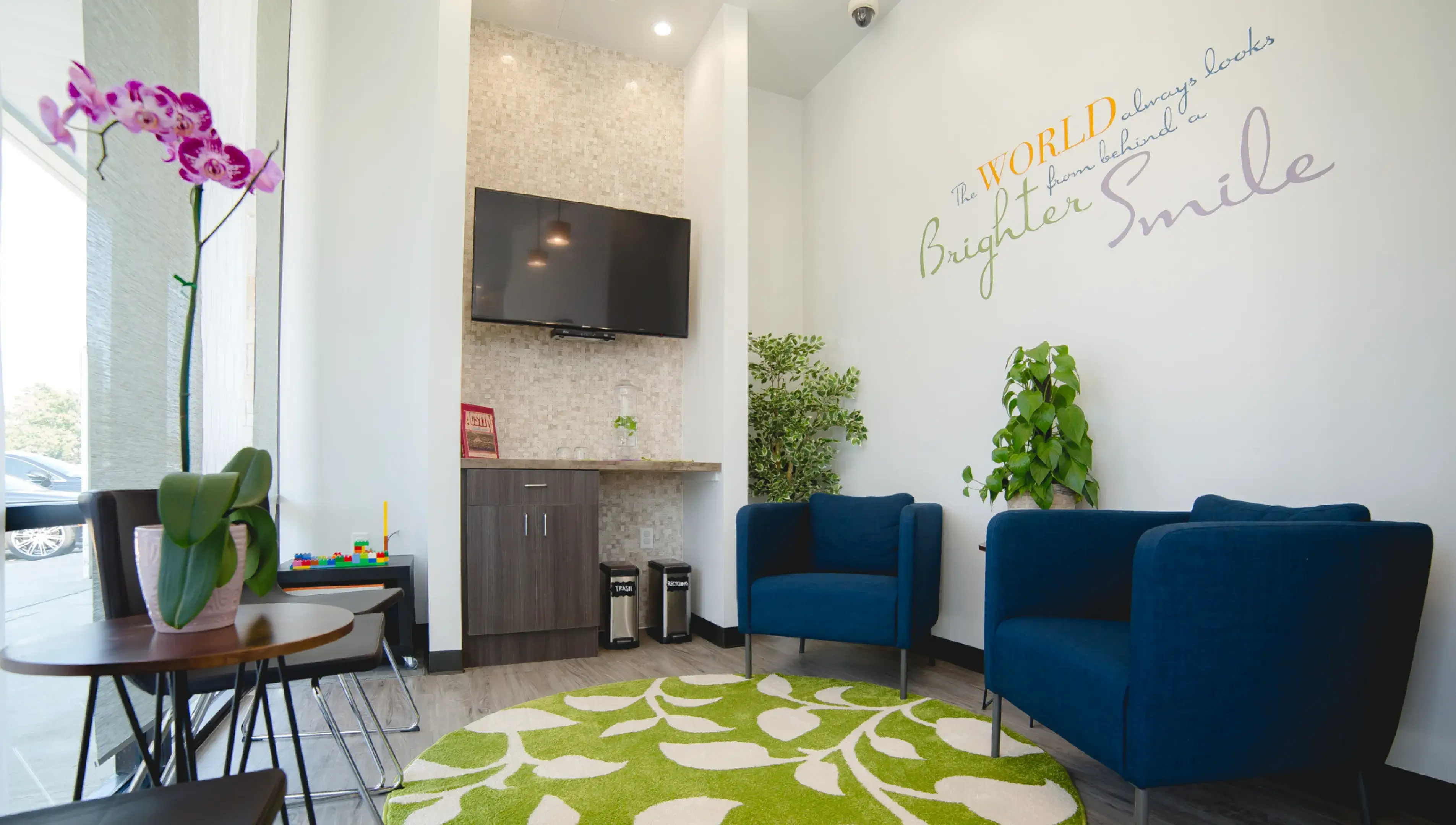 A living room with two blue chairs and a green rug.