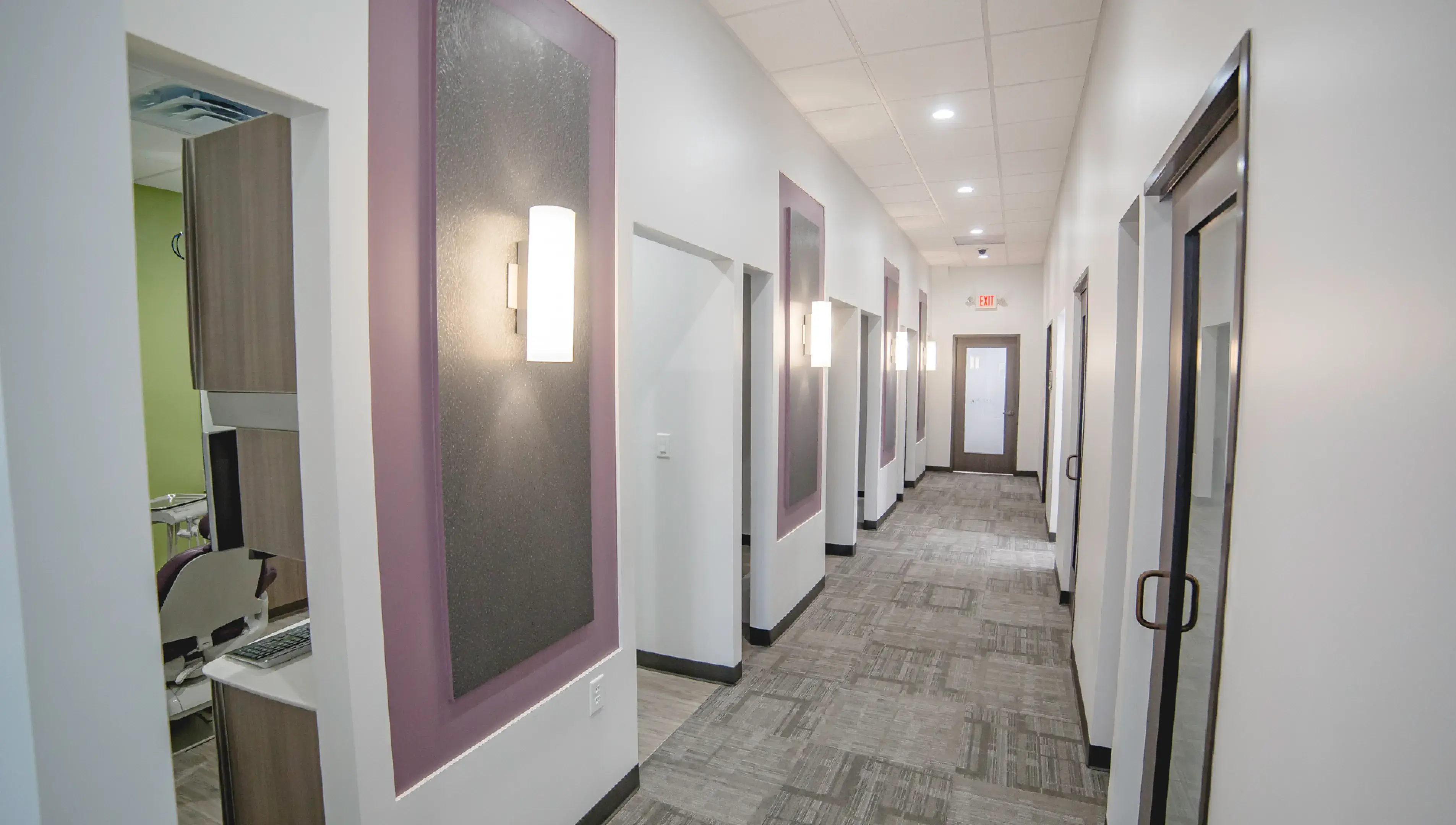 A long hallway with several doors and a mirror on the wall.