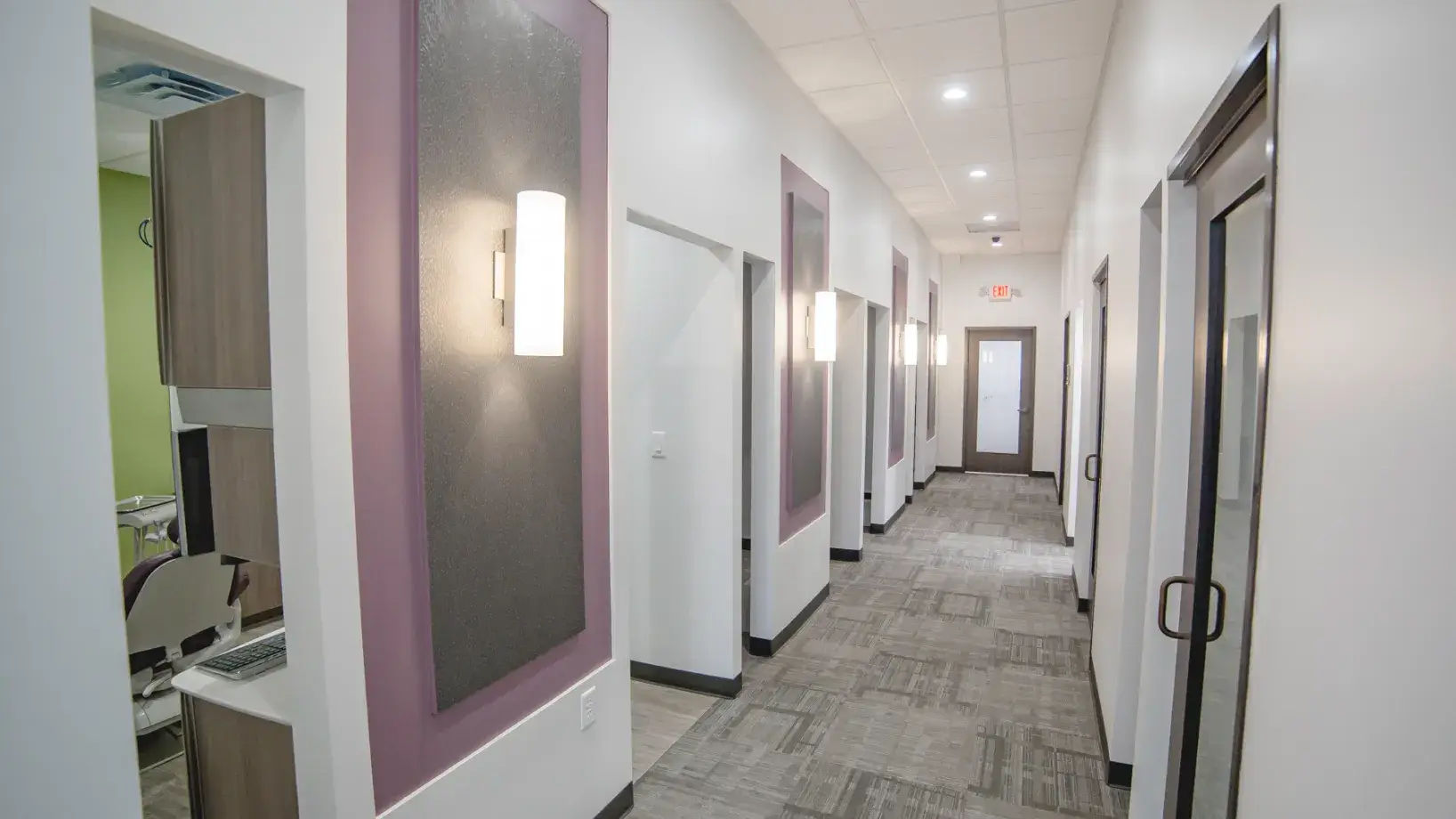 A long hallway with several doors and a mirror on the wall.