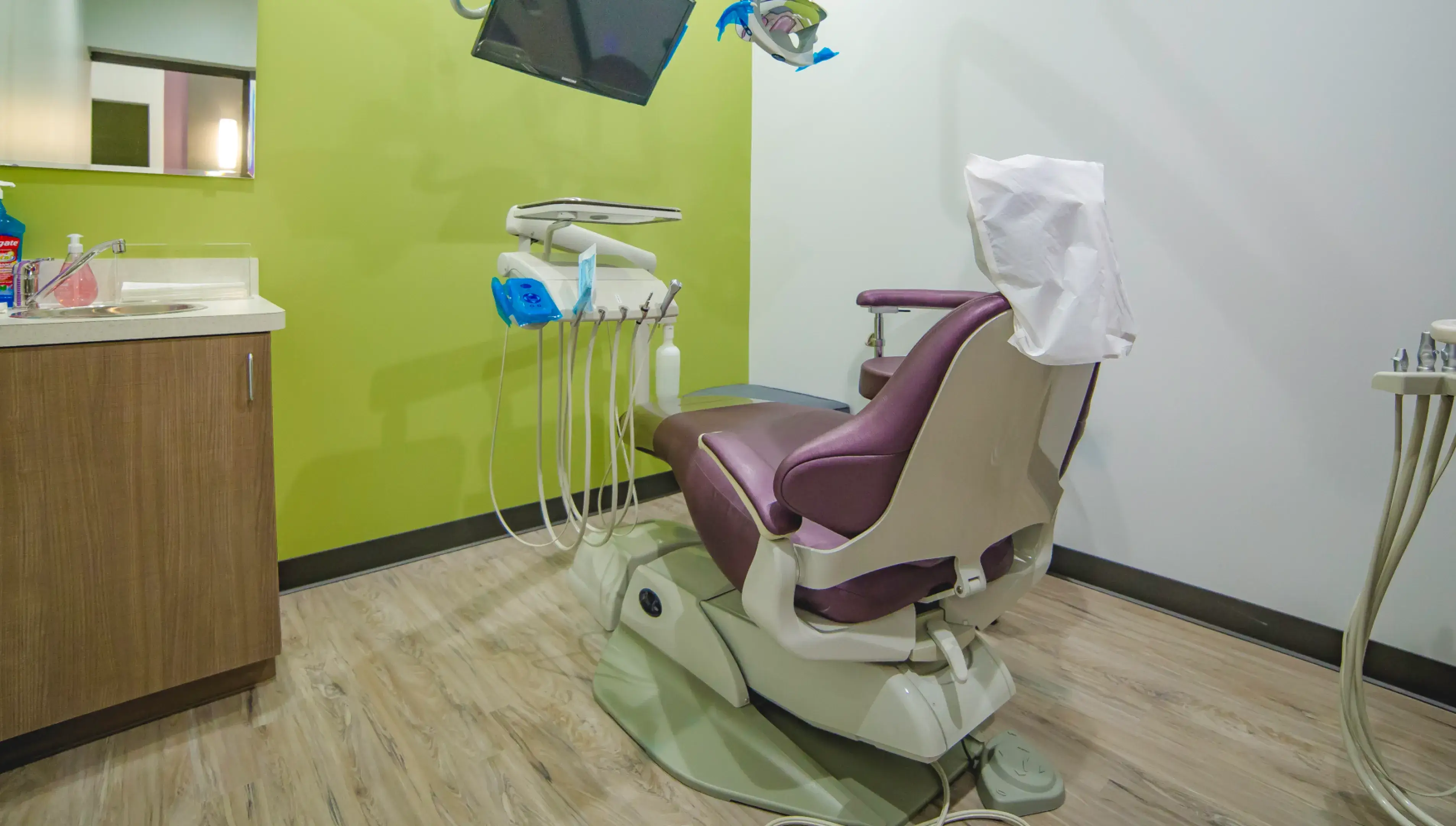 A dentist chair in a room with a tv.