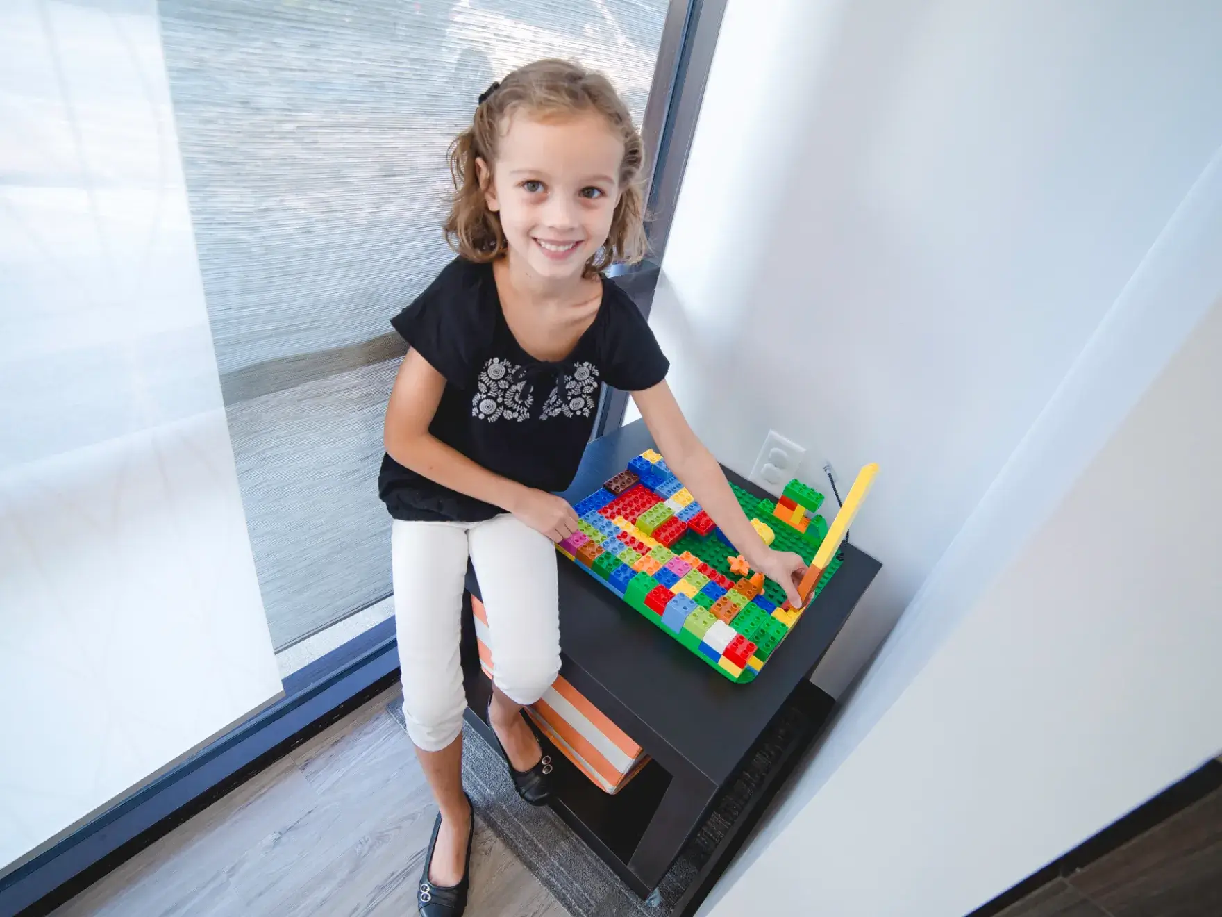 A little girl playing with a colorful building block set.