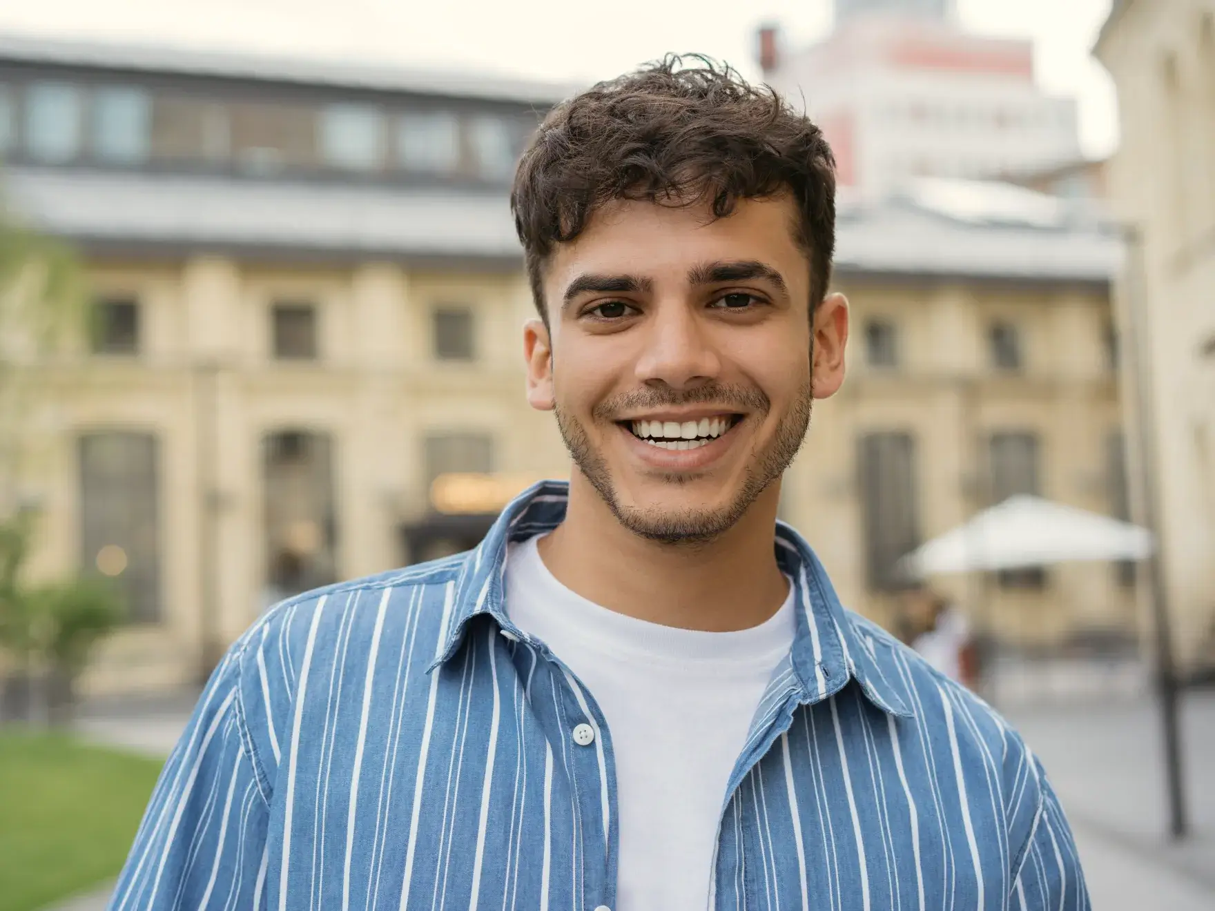 a young man smiling in front of a building